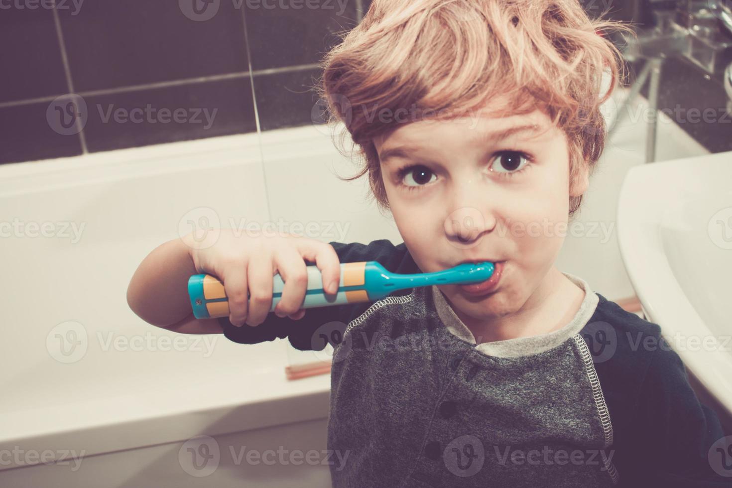 piccolo ragazzo spazzolatura denti nel il bagno. foto