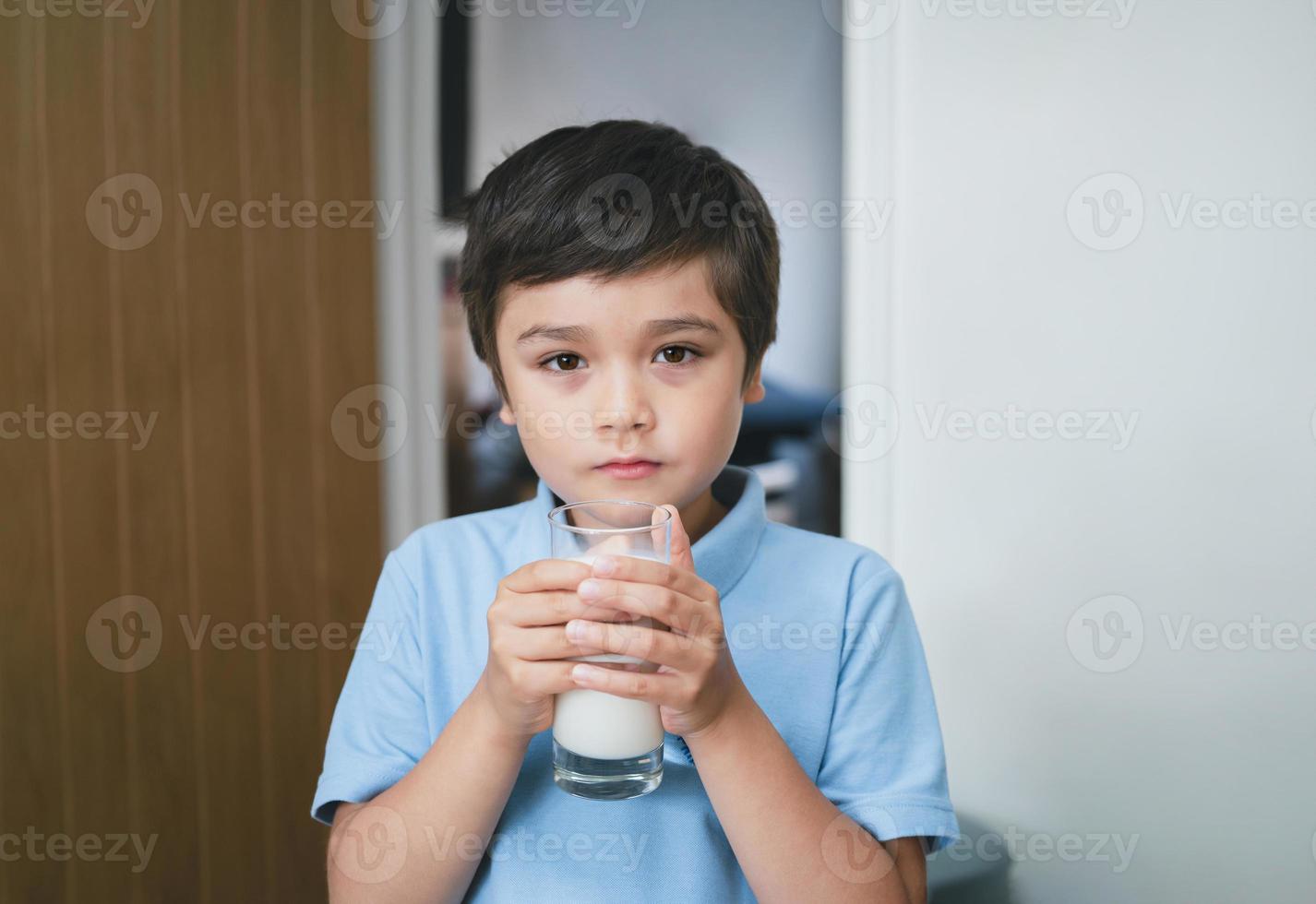 ritratto salutare scuola ragazzo potabile bicchiere di latte per colazione, contento bambino in piedi nel cucina potabile caldo latte prima partire per scuola. sano cibo stile di sollevamento concetto foto