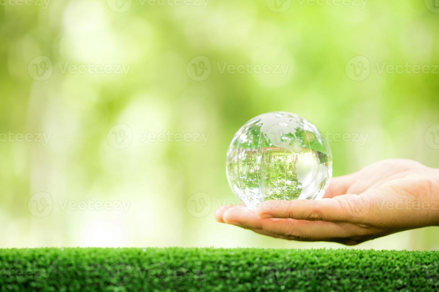 umano mano Tenere globo pianeta bicchiere nel verde foresta con bokeh natura luci. mondo ambiente giorno. concetto per ambiente conservazione, proteggere ecologia terra e ambientale eco-friendly vita. foto