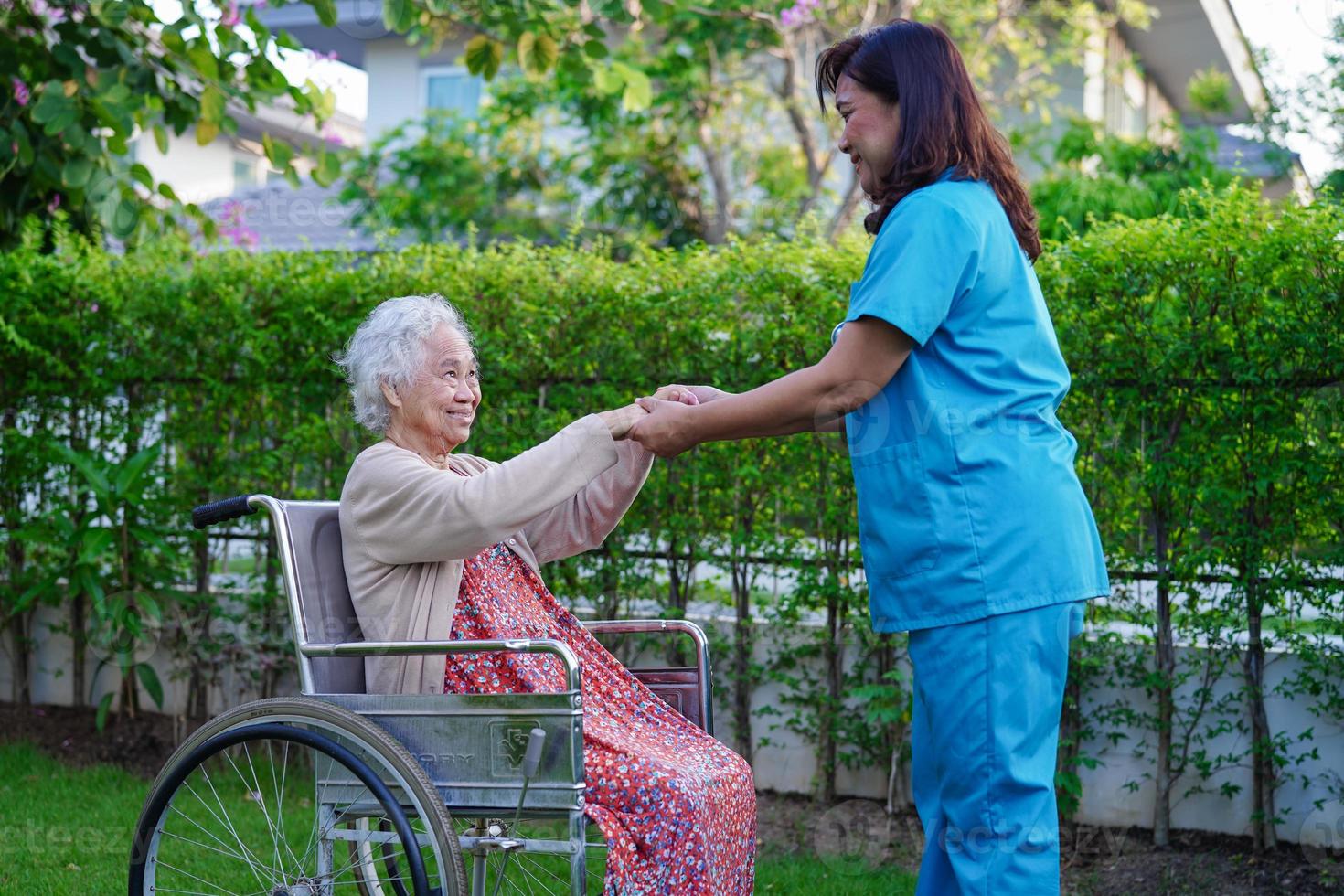 il medico aiuta il paziente asiatico della disabilità della donna anziana che si siede sulla sedia a rotelle nel parco, concetto medico. foto