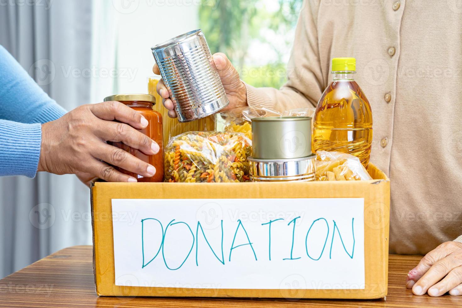 volontari che mettono vari alimenti secchi nella scatola delle donazioni per aiutare le persone. foto
