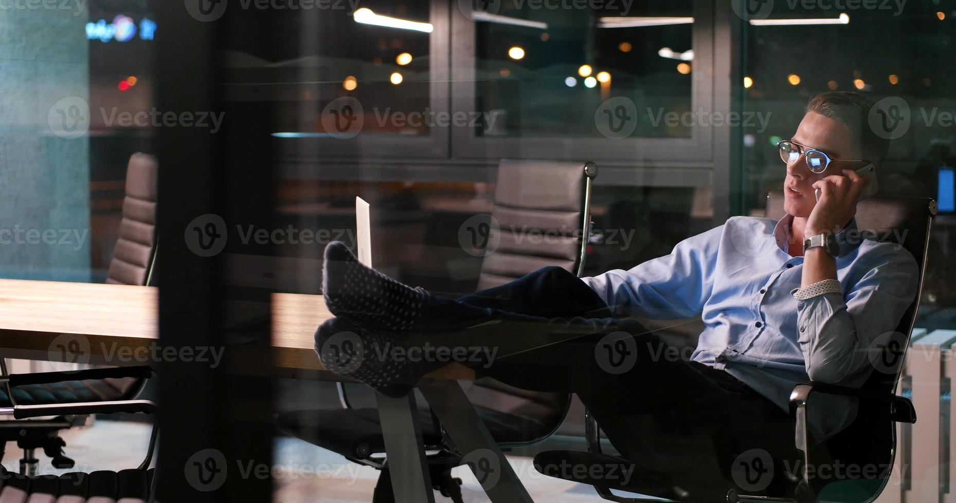 uomo d'affari seduta con gambe su scrivania a ufficio foto