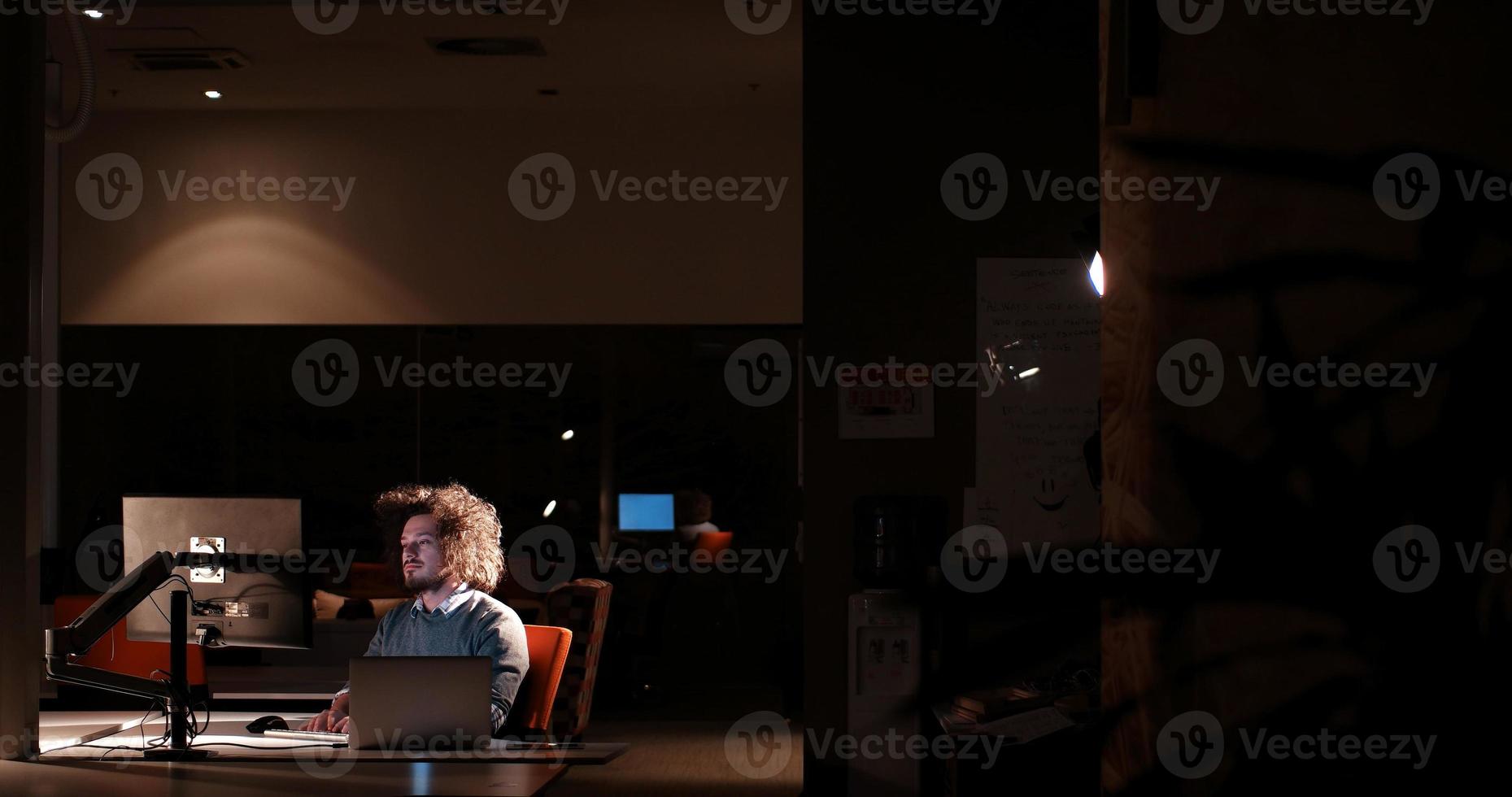 uomo Lavorando su computer nel buio ufficio foto