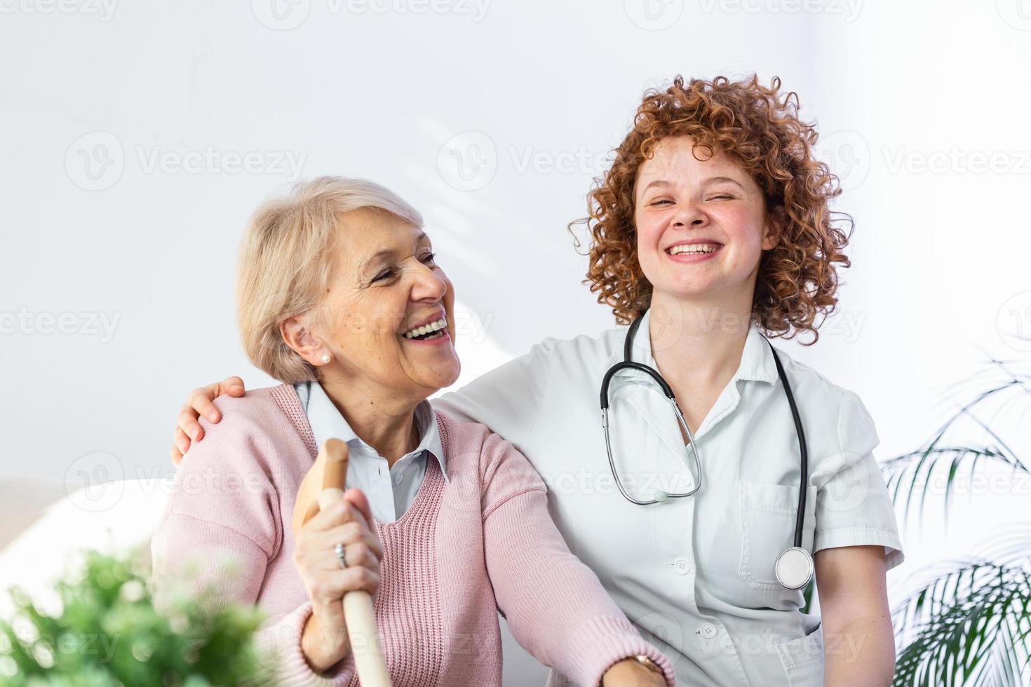 giovane badante e anziano donna ridendo insieme mentre seduta su divano. anziano donna e minore amico avendo divertimento insieme durante incontro a casa. foto