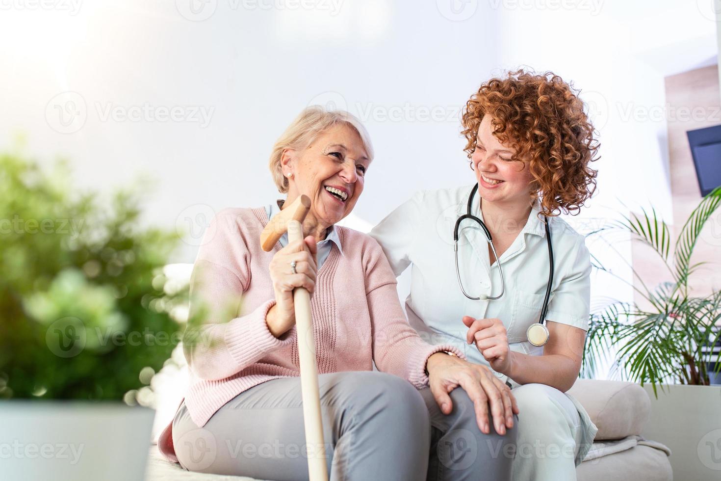 amichevole relazione fra sorridente badante nel uniforme e contento anziano donna. supporto giovane infermiera guardare a anziano donna. giovane cura bello badante e contento reparto foto