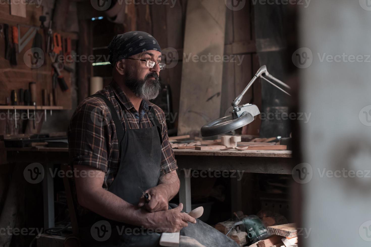 cucchiaio maestro nel il suo laboratorio con di legno prodotti e utensili foto