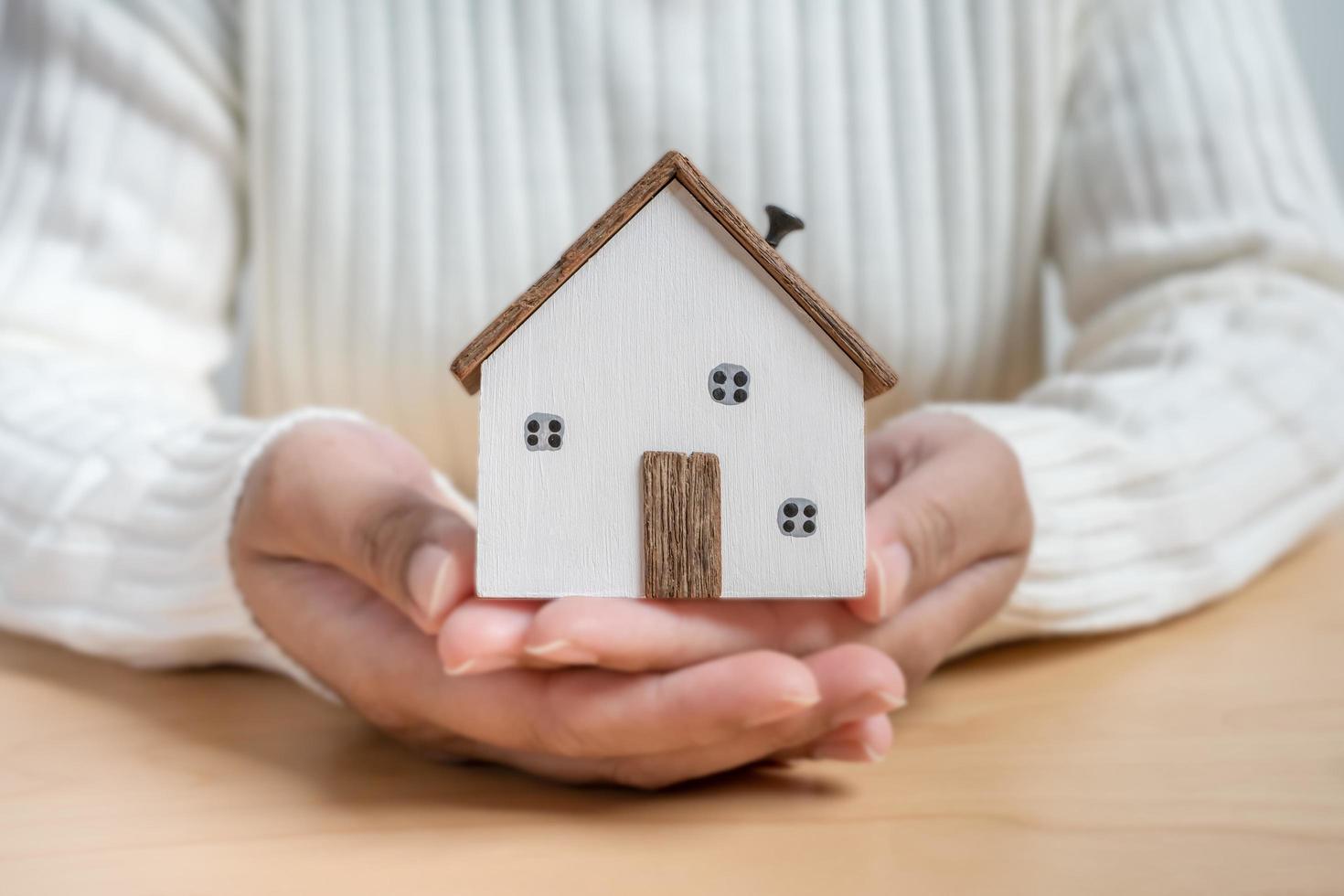 mani Tenere piccolo di legno Casa concetto di protezione o Salvataggio per nuovo Residenziale progetto. foto