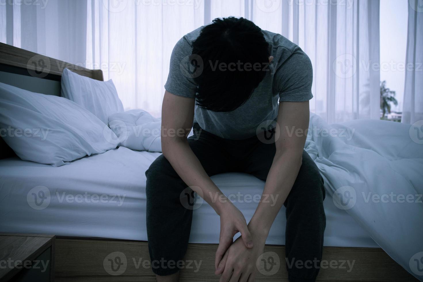 stressato asiatico giovane uomo seduta solo su letto. cattivo relazione o fallito problema e malattia concetto. foto
