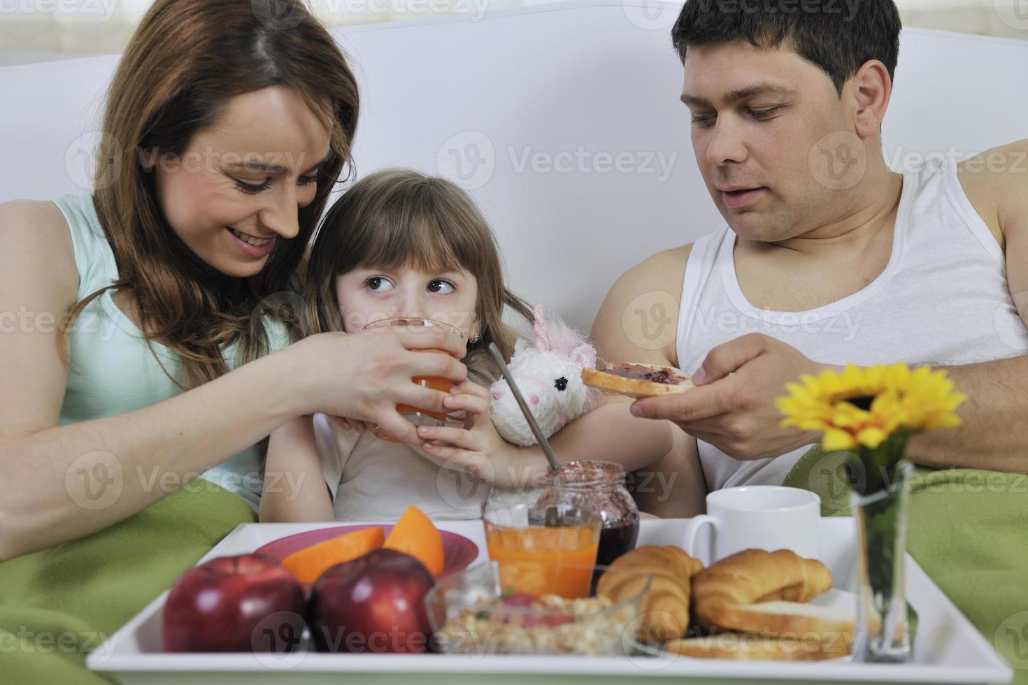 contento giovane famiglia mangiare prima colazione nel letto foto