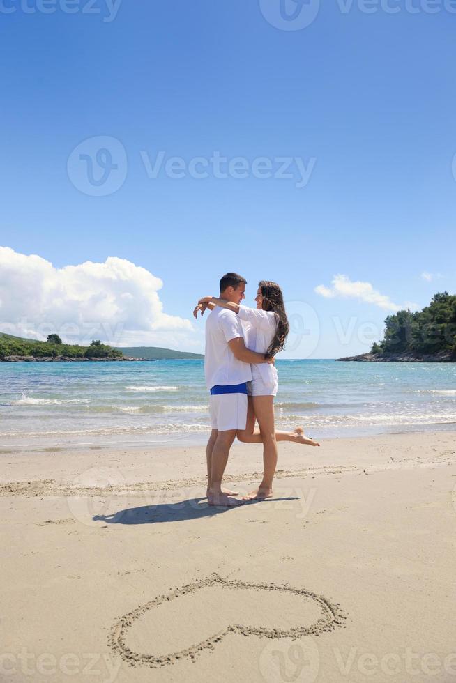 contento coppia avere divertimento su il spiaggia con cuore su sabbia foto