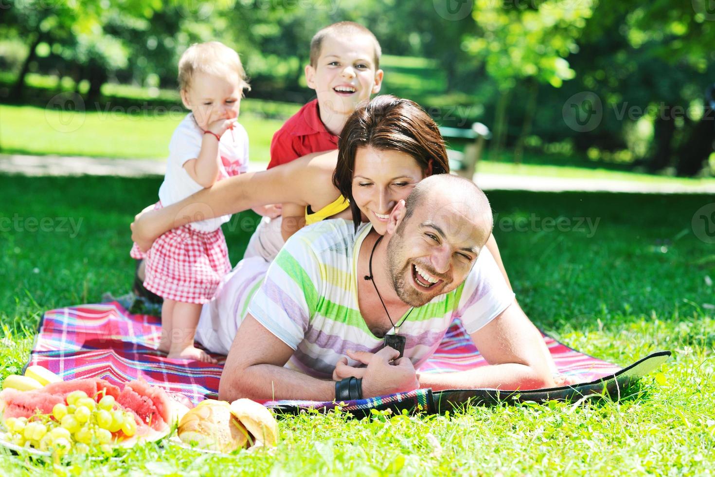 felice giovane coppia con i loro bambini si divertono al parco foto