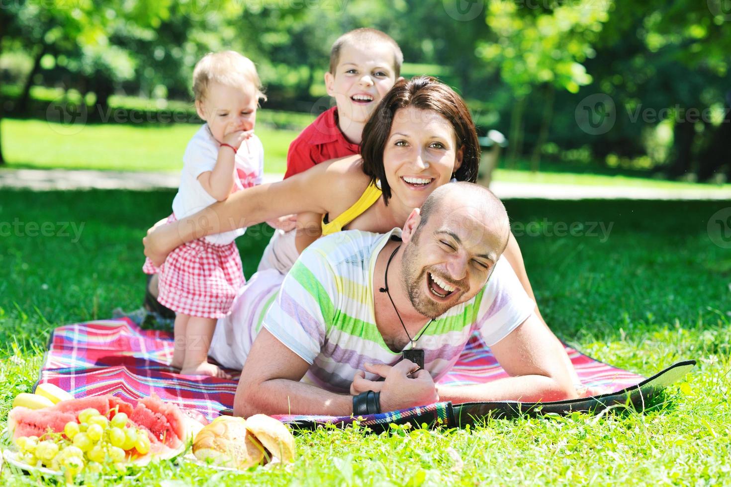 felice giovane coppia con i loro bambini si divertono al parco foto