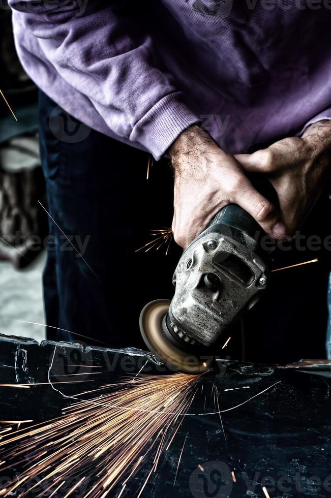 lavoratore industriale utilizzando una piccola smerigliatrice per tagliare il metallo foto