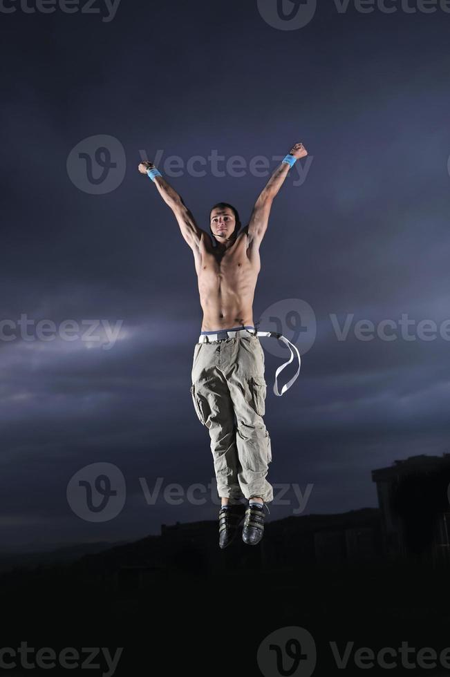 giovane uomo danza e salto su superiore di il edificio foto