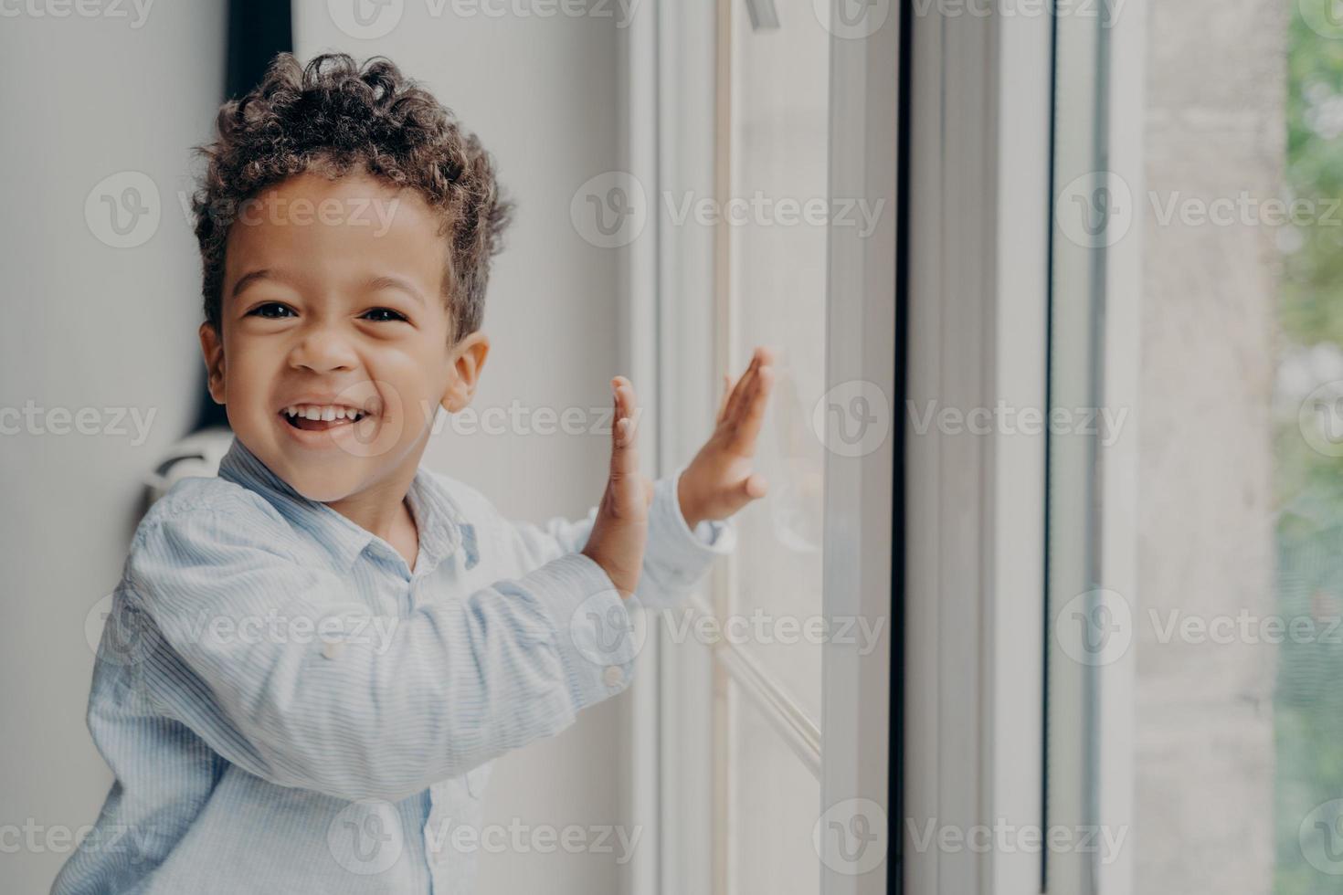 ritratto di un ragazzino nero gioioso con un sorriso adorabile che si diverte a casa foto