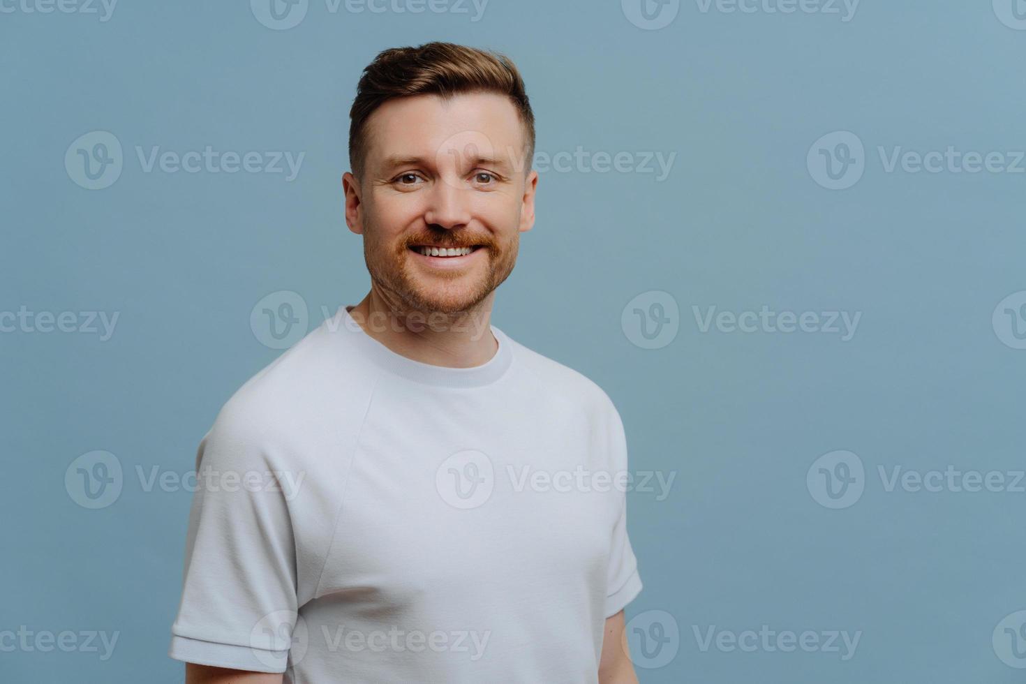 giovane uomo bello positivo in abbigliamento casual in posa in studio foto