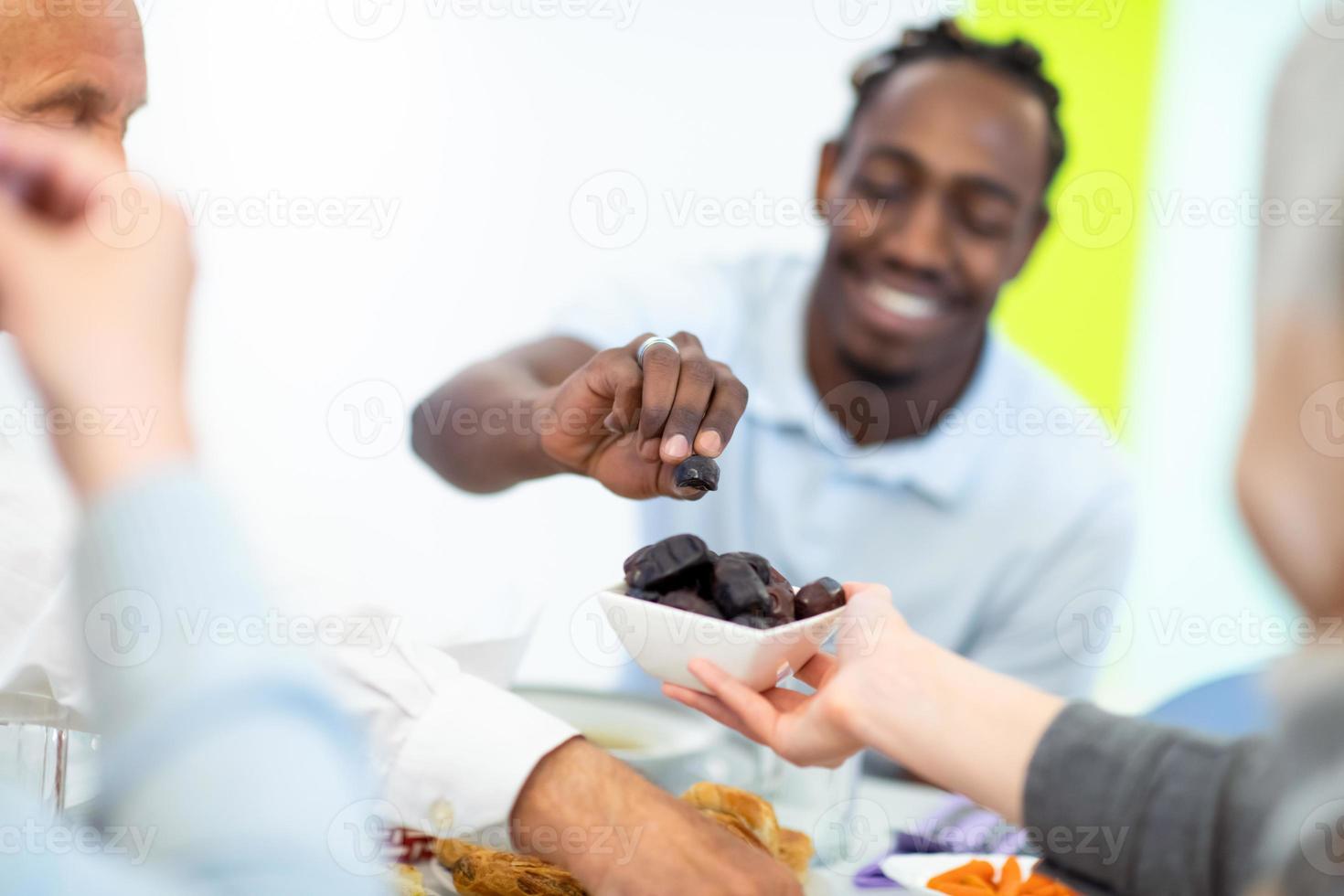 moderno multietnico musulmano famiglia condivisione un' ciotola di date foto