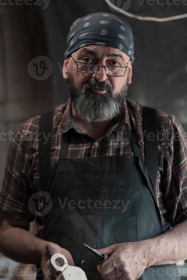 cucchiaio maestro nel il suo laboratorio con di legno prodotti e utensili foto