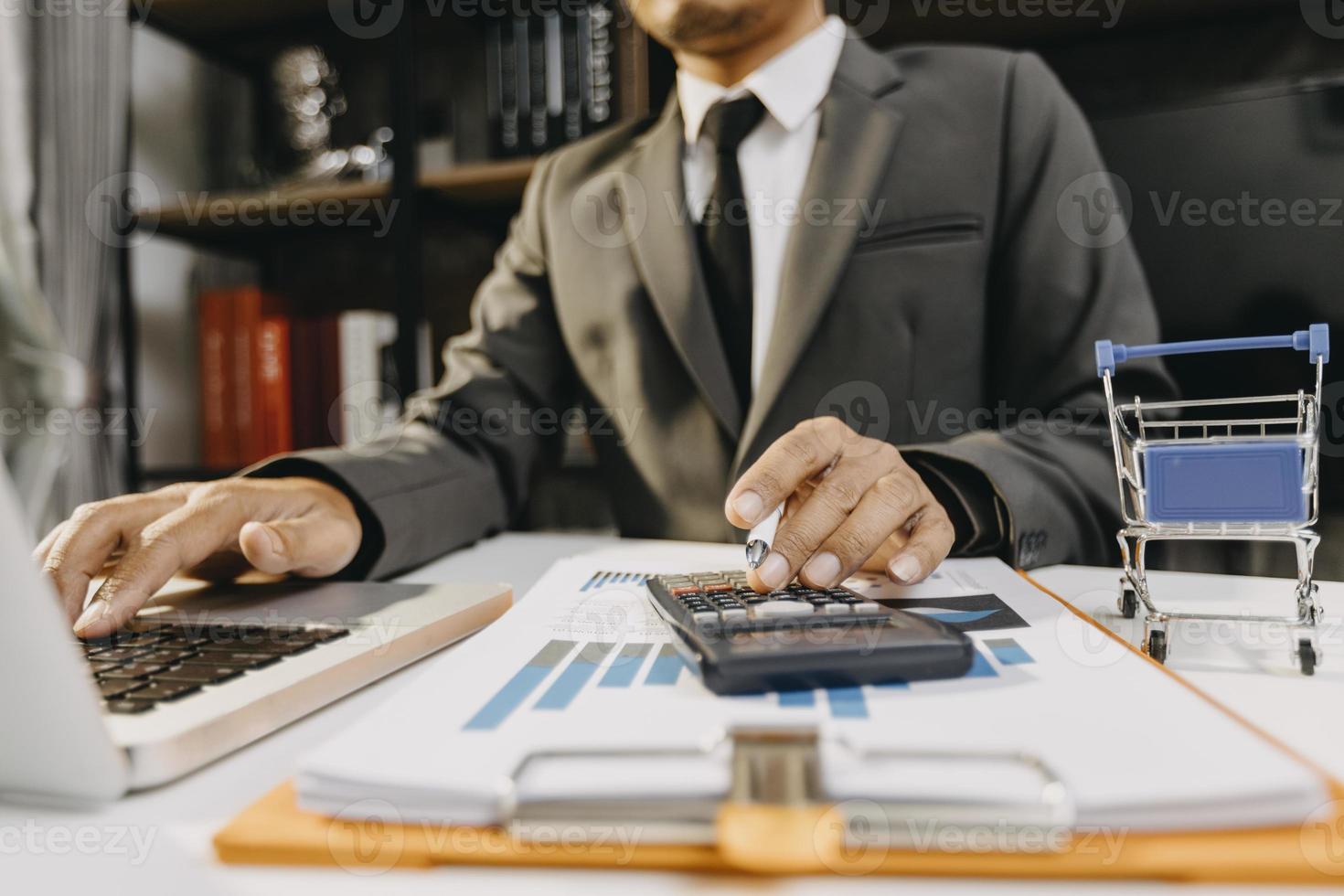 concetto di contabilità aziendale, uomo d'affari che utilizza la calcolatrice con computer portatile, budget e carta di prestito in ufficio. foto