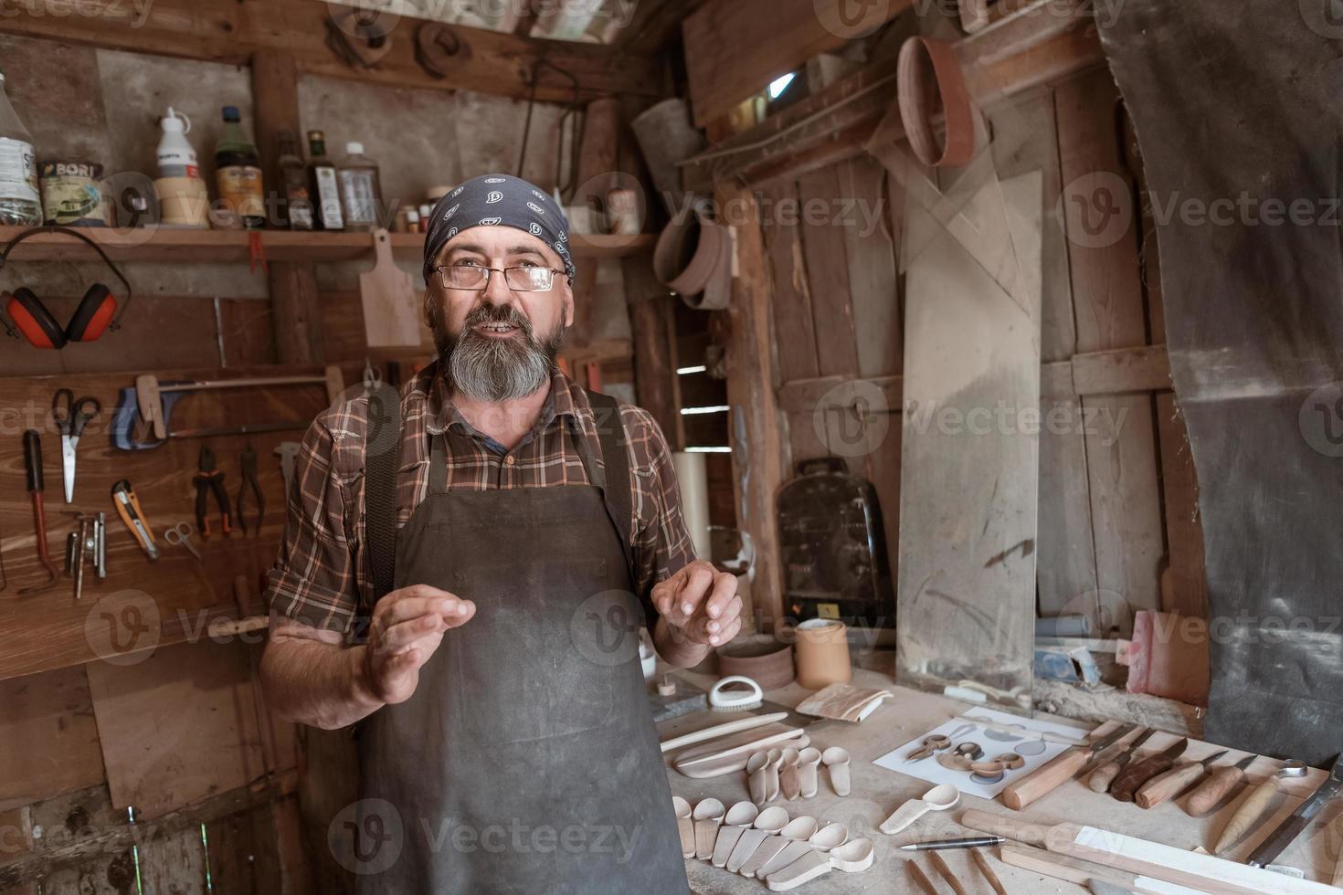 cucchiaio maestro nel il suo laboratorio con di legno prodotti e utensili foto