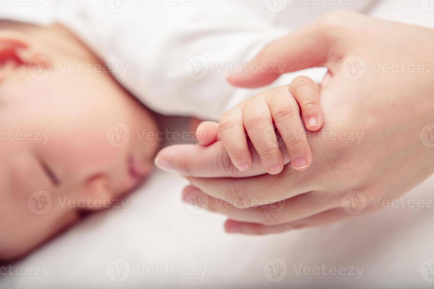 mano il addormentato bambino nel il mano di madre avvicinamento foto