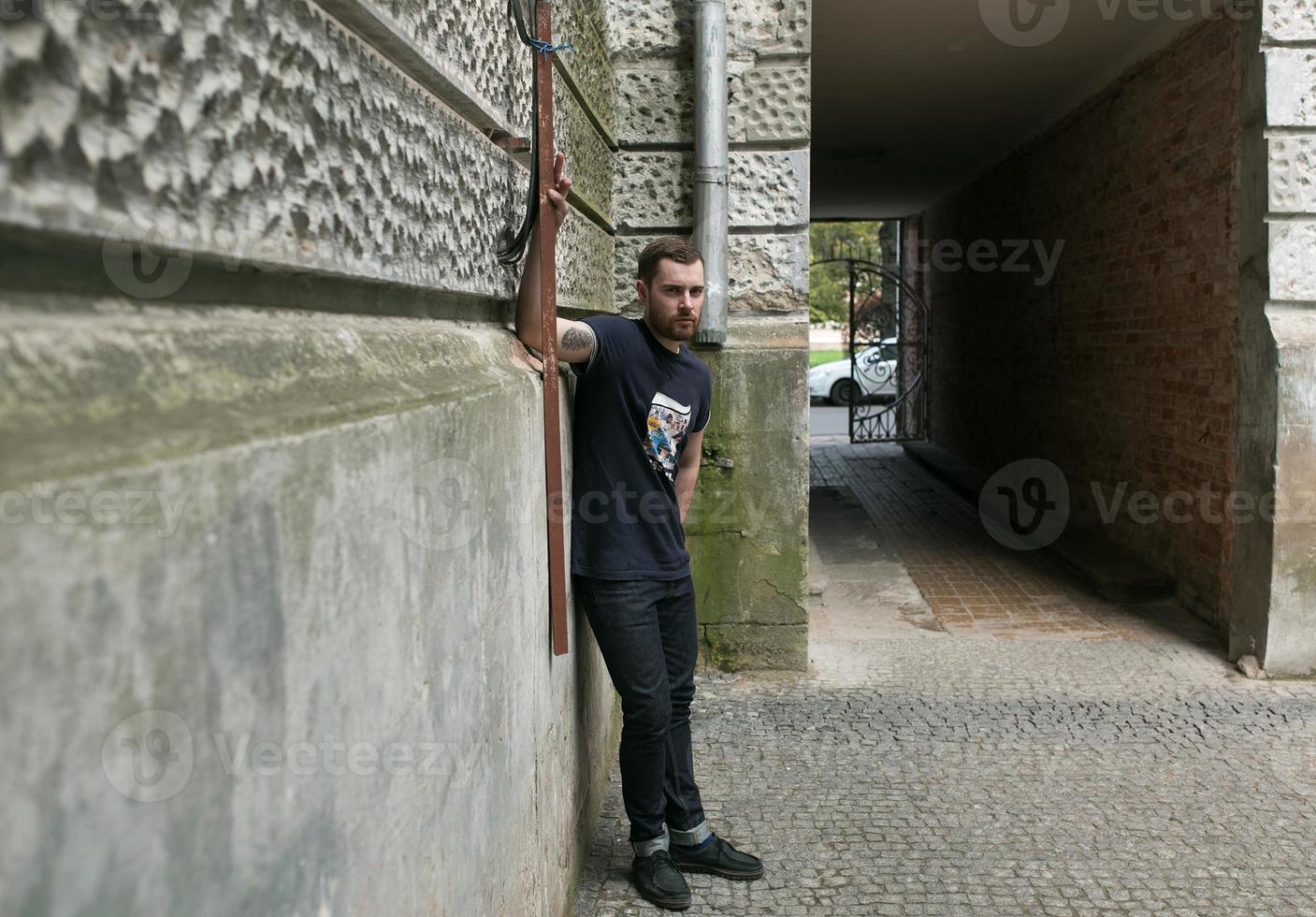 l'uomo con gli stivali autentici e i jeans a cimosa sullo sfondo della città vecchia foto