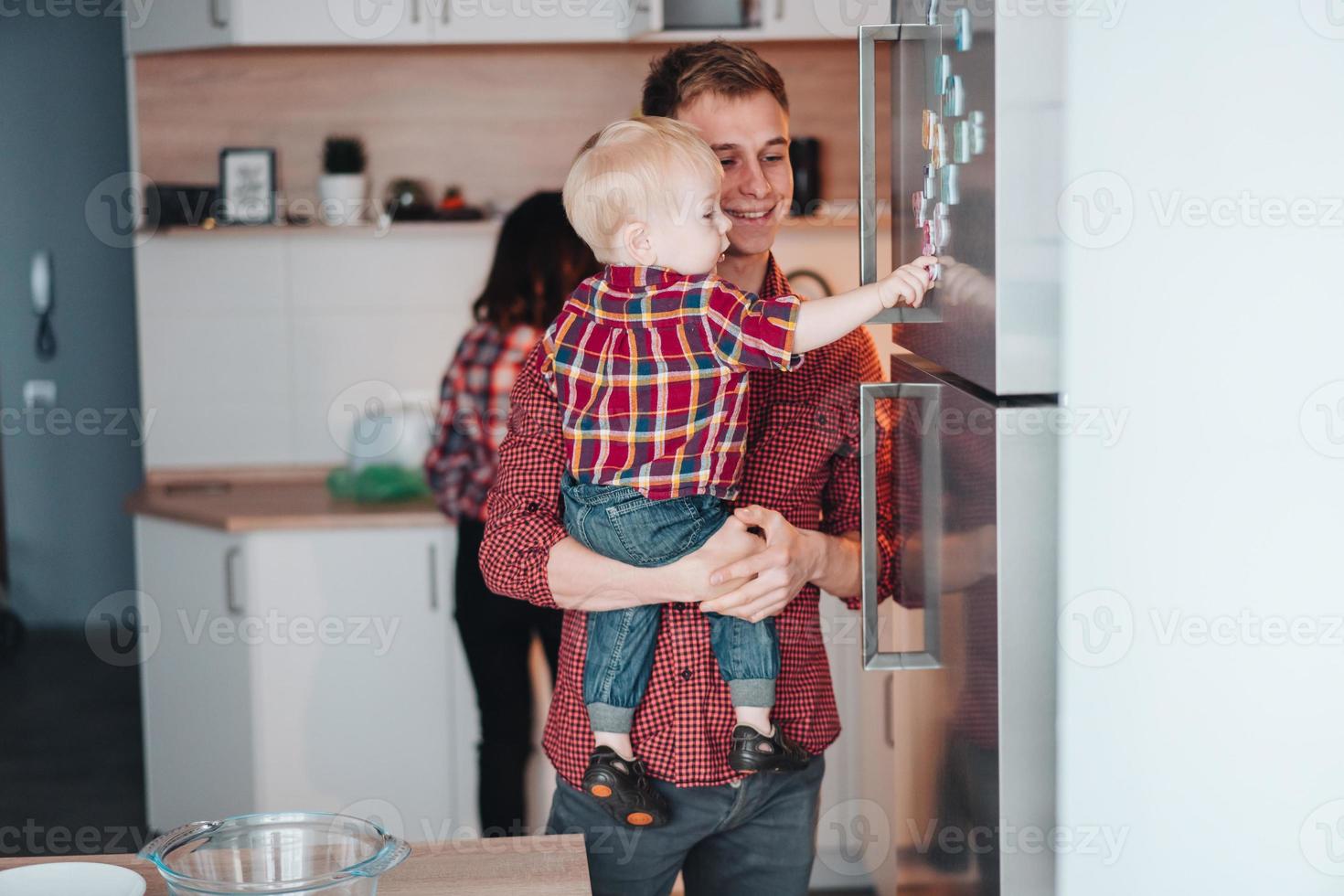 papà e poco figlio nel il cucina di il frigo foto
