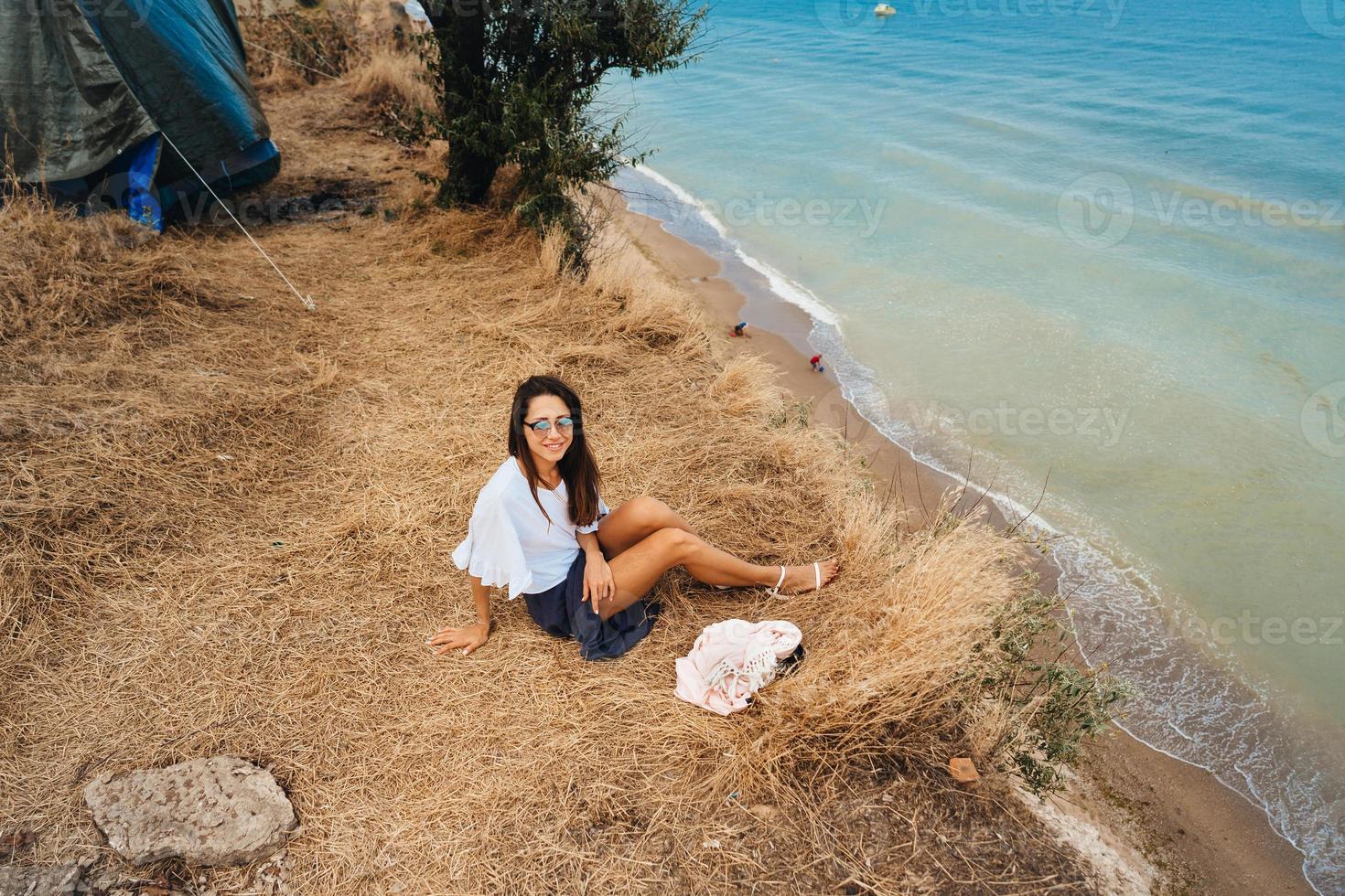 attraente donna nel estate gonna e camicia si siede su il riva foto
