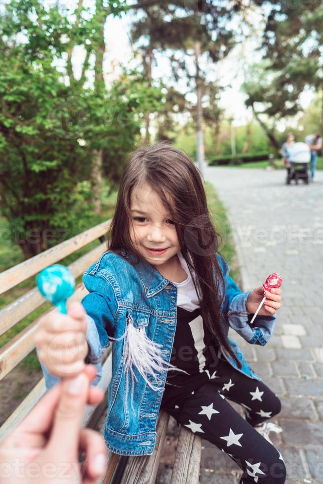 ragazza seduta su panchina con caramelle foto