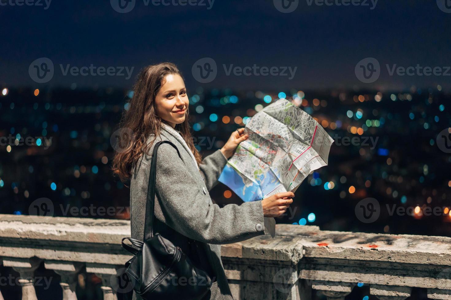 ragazza con un' carta geografica su il sfondo di il notte città foto