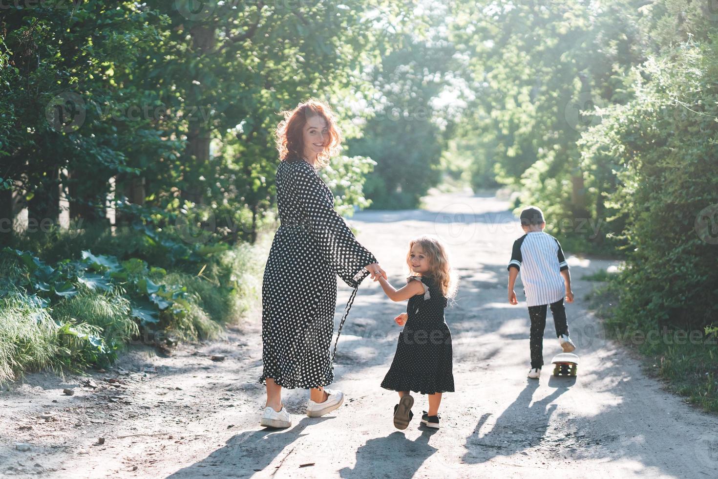 un' donna a piedi con sua bambini su il strada foto