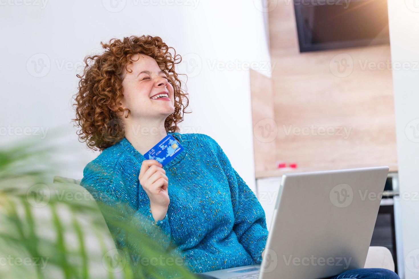 giovane donna Tenere credito carta e utilizzando il computer portatile computer. in linea shopping concetto. contento donna fare in linea shopping a casa foto