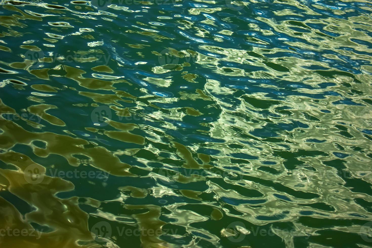 acqua ondulazione struttura sfondo. ondulato acqua superficie durante tramonto, d'oro leggero riflettendo nel il acqua. foto