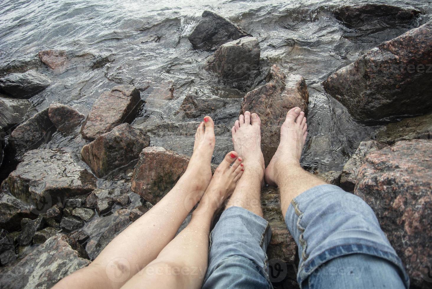 il tipo e il ragazza siamo riposo su il mare. piedi di il acqua foto