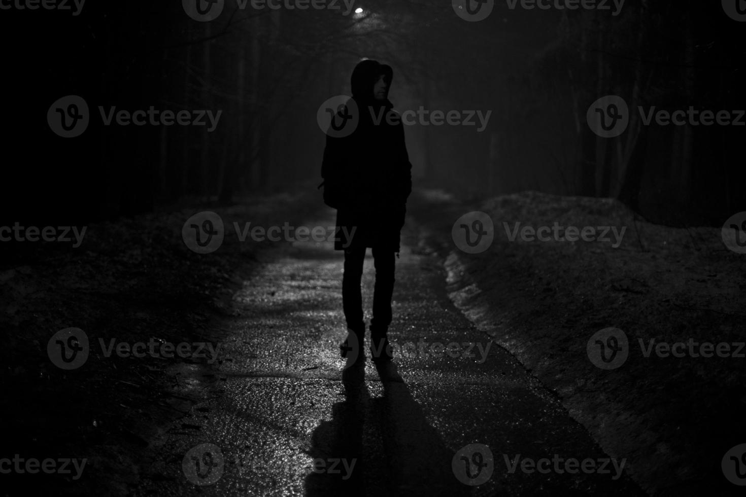 silhouette di uomo a notte nel parco. uomo passeggiate solo su strada nel sera. foto