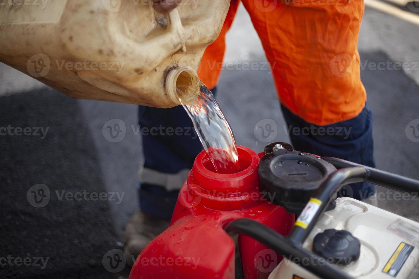 scatola metallica di benzina. diesel motore rifornimento. lavoratore versa carburante in cisterna. foto