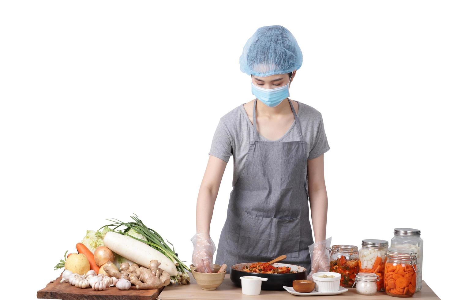 asiatico donna fabbricazione kimchi lei indossa un' maschera, guanti e un' protettivo berretto per mantenere cibo pulire. bianca sfondo. coreano fermentato cibo concetto fatto a partire dal verdure. ritaglio sentiero. isolato foto