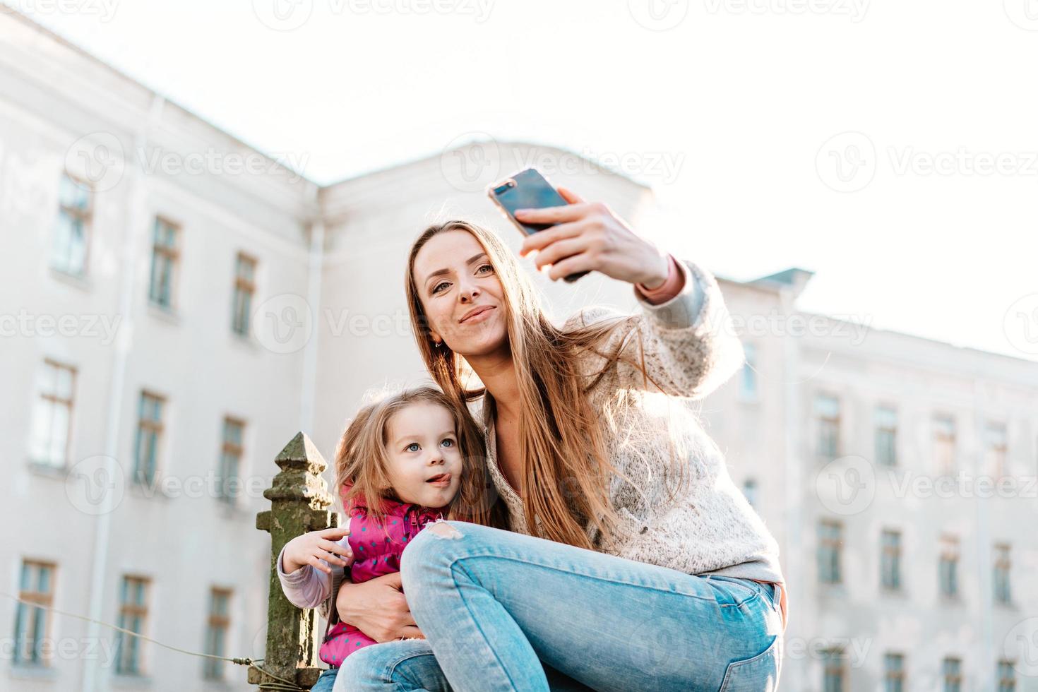 mamma e figlia sedersi insieme su il recinto foto