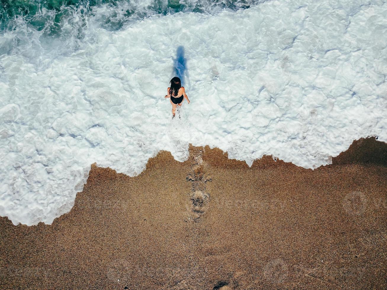 aereo superiore Visualizza giovane donna su il sabbia spiaggia foto
