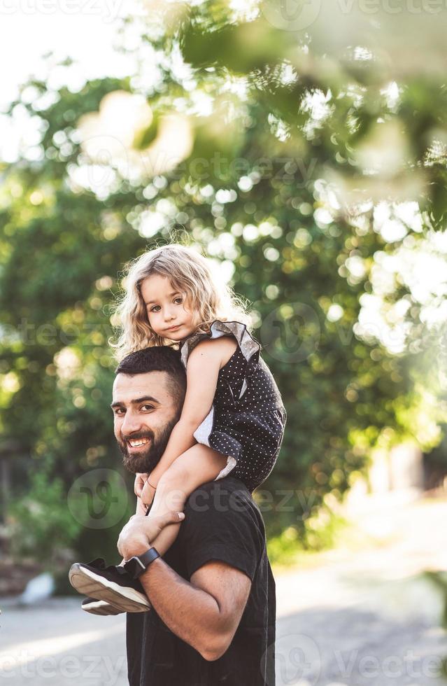 un' poco figlia si siede su il le spalle foto