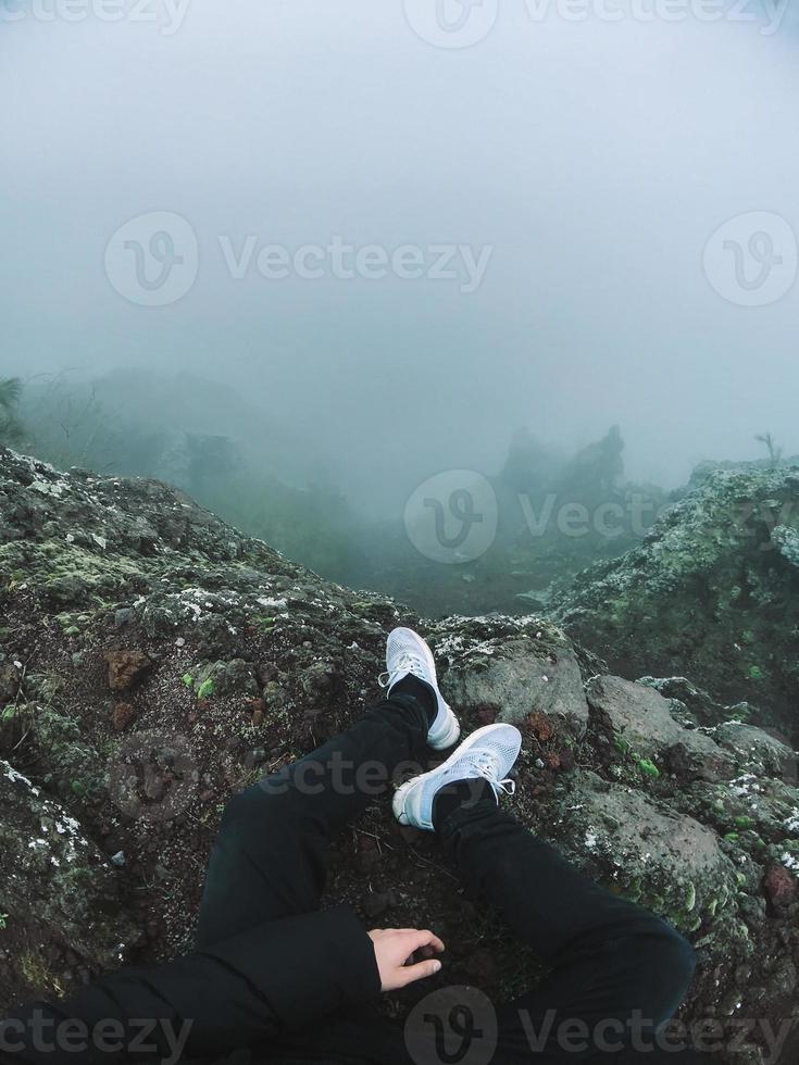 uomo su scogliera Guarda a il nebbia foto