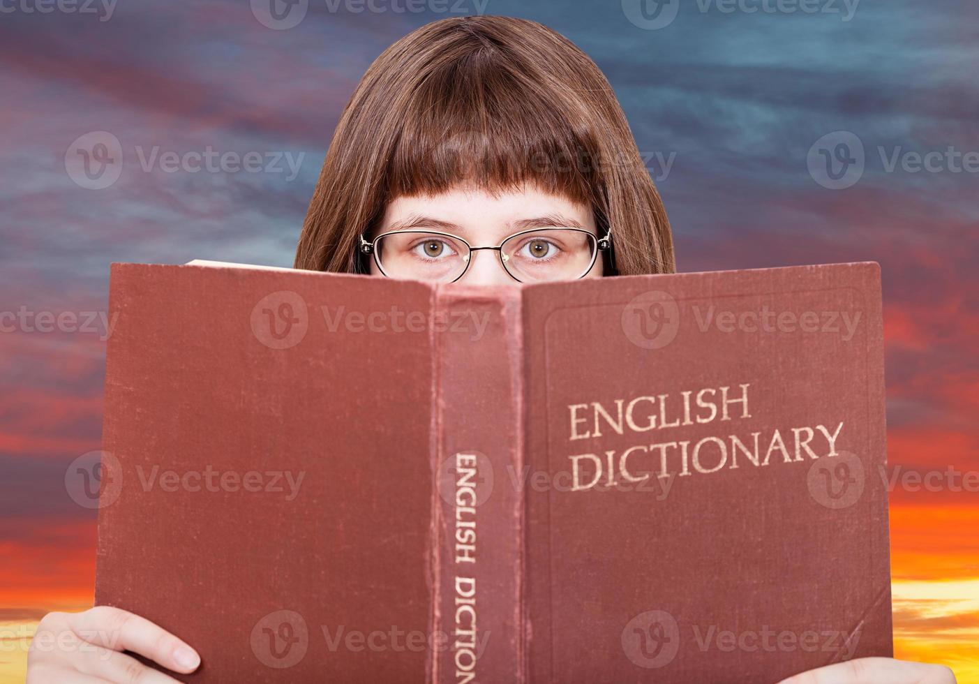 ragazza sembra al di sopra di inglese dizionario e tramonto cielo foto