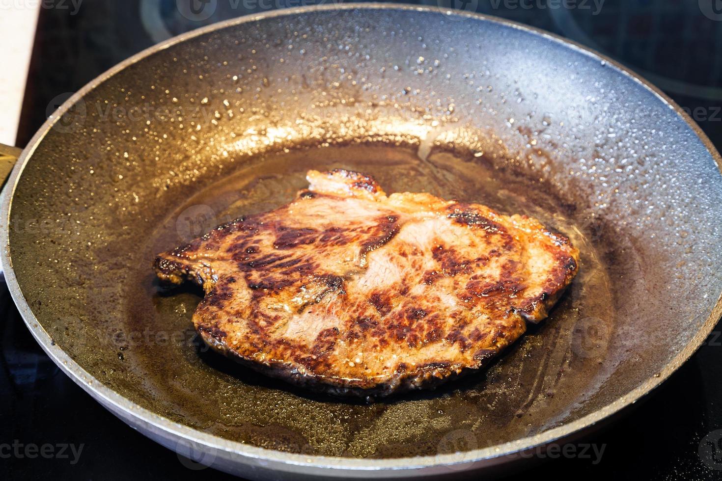 frittura Manzo bistecca nel padella su ceramica elettrico gamma foto