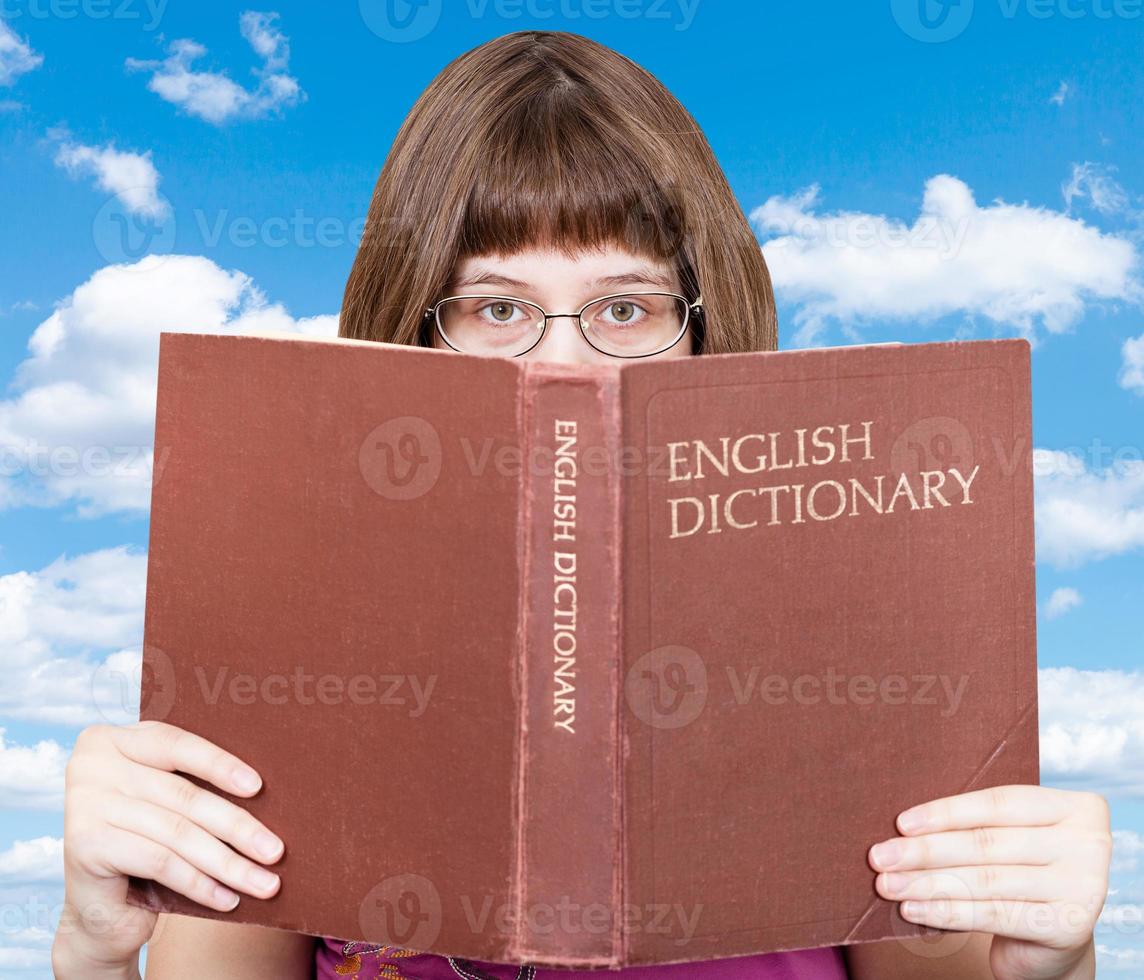 ragazza sembra al di sopra di inglese dizionario e blu cielo foto