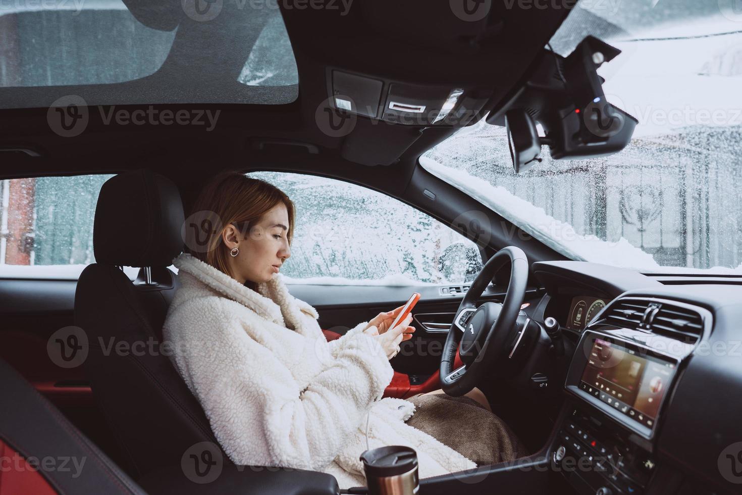 attraente donna autista nseduto dietro a il timone ruota nel sua auto foto