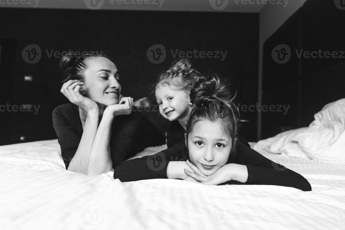 mamma e Due figlie avere divertimento su il letto foto