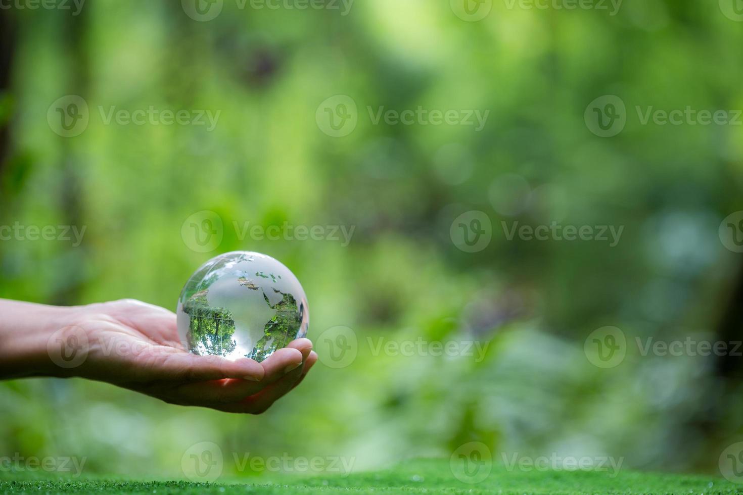 umano mano Tenere globo pianeta bicchiere nel verde foresta con bokeh natura luci. mondo ambiente giorno. concetto per ambiente conservazione, proteggere ecologia terra e ambientale eco-friendly vita. foto