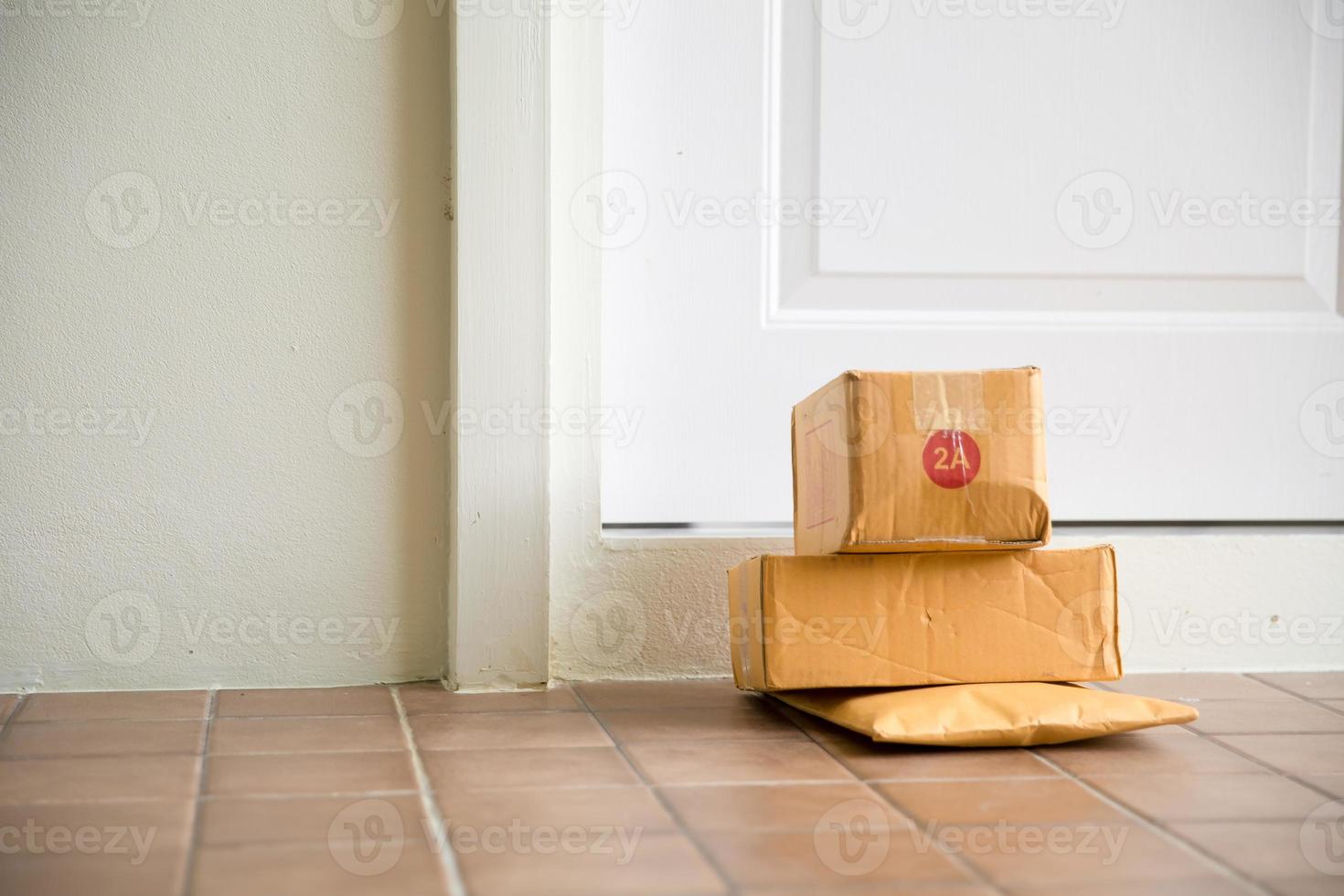 cartone pacco scatola vicino porta su pavimento. in linea acquisti, scatole consegnato per il tuo davanti porta. facile per rubare quando nessuno è casa. pacco nel cartone scatola su porta di casa. consegna servizio foto