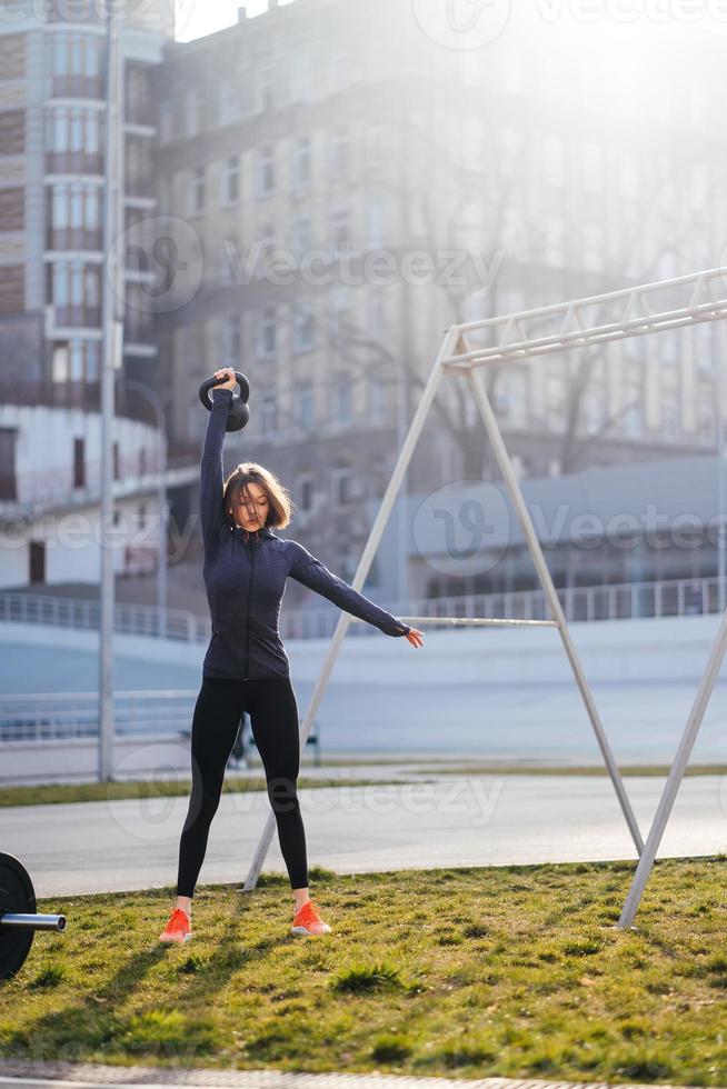 giovane donna esercizio con un' kettlebell al di fuori a stadio foto