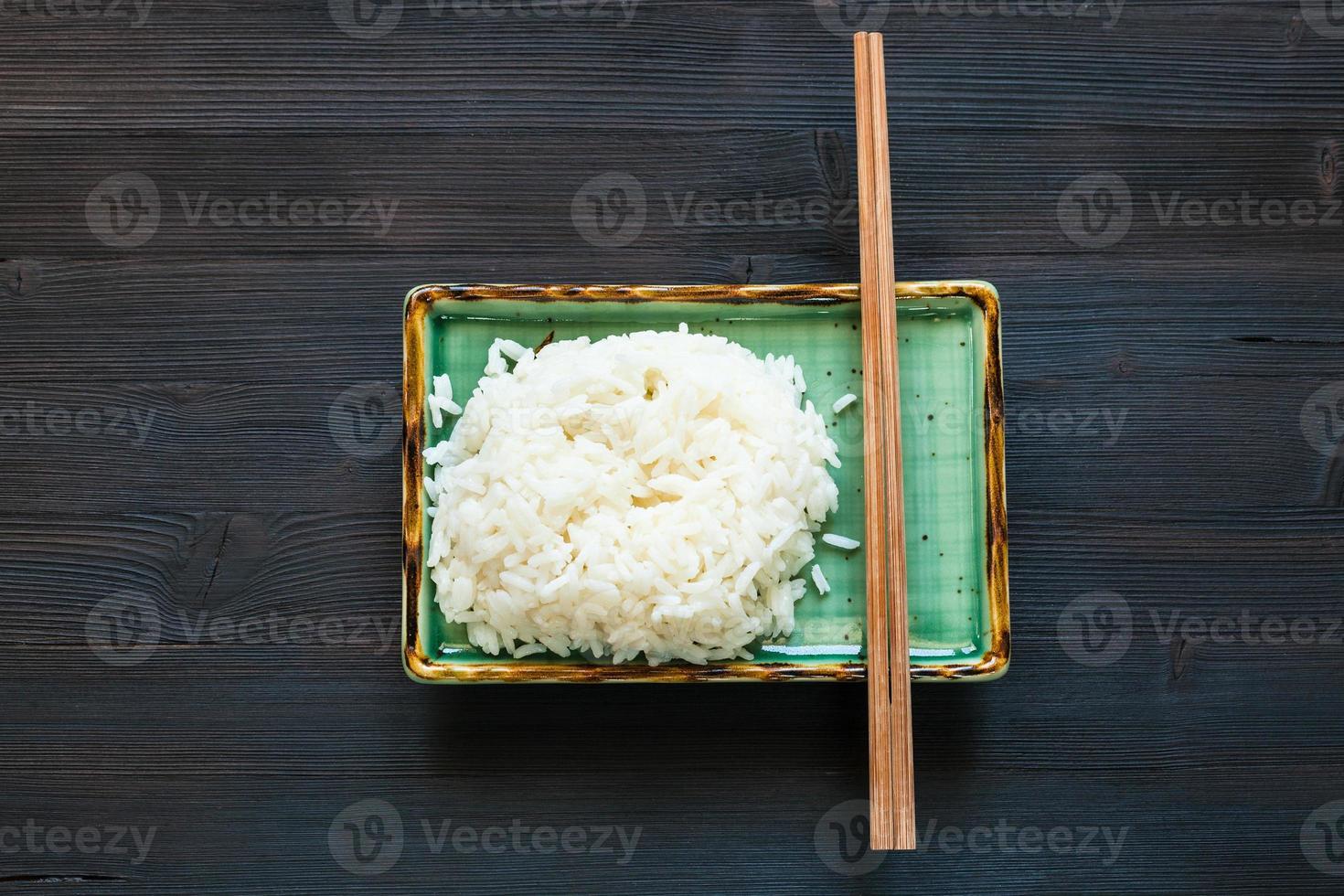 bollito riso e bastoncini su verde piatto su buio foto